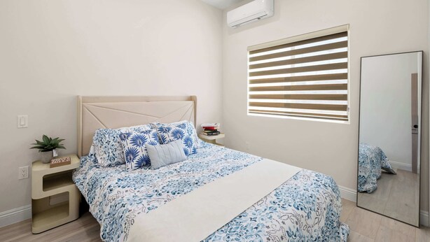 Un dormitorio con cama, mesita de noche y ventana con persianas.