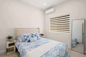 A bedroom with a bed, bedside table, nightstand, and a window with blinds. - Cozy Modern Home w Full Kitchen & Parking (Baldwin Park)