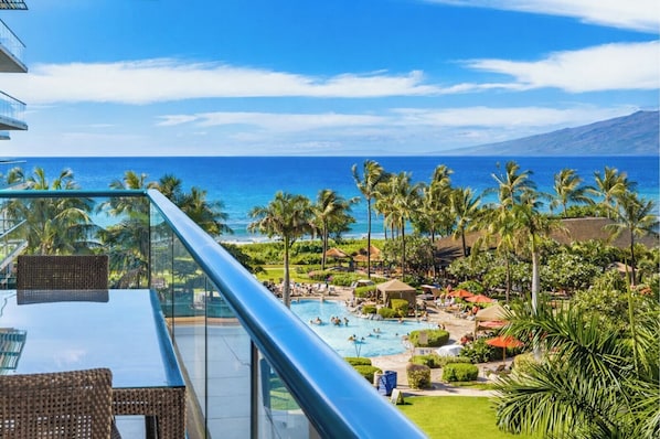 A resort with a pool, palm trees, and a view of the ocean.