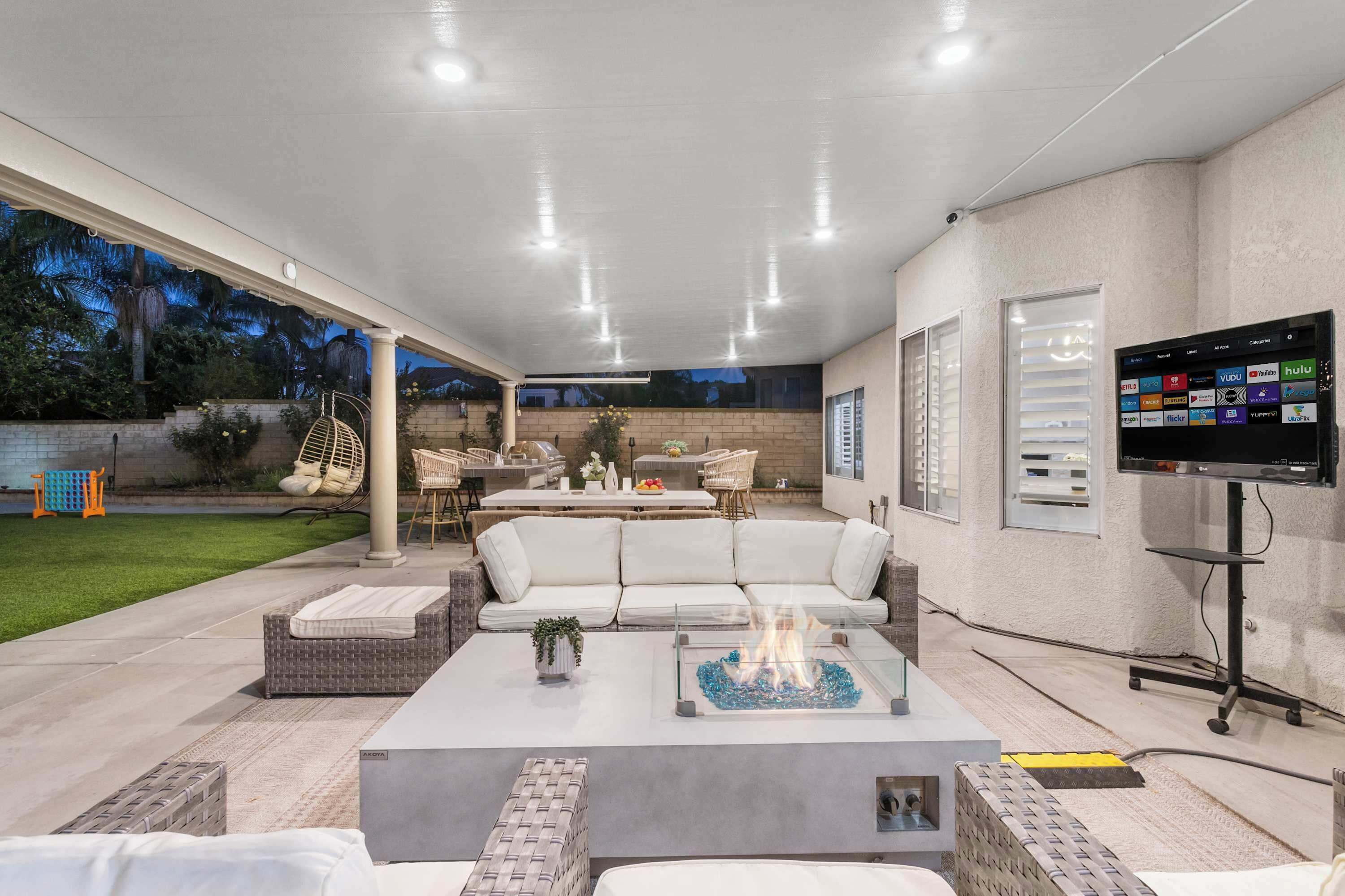 A modern outdoor living area with a sofa, coffee table, and fire feature.