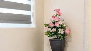 Un rincón con ventana, una planta en maceta y una consola de madera con estantes.