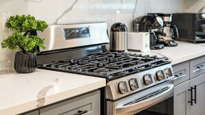 Una cocina moderna con electrodomésticos de acero inoxidable, salpicadero de mármol y muebles grises.