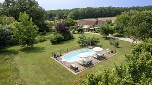 A rectangular swimming pool with a deck, surrounded by a fence, and a covered area with umbrellas. - Gîte for 2 people with swimming pool - In the heart of Périgord noir (Saint-Cyprien)