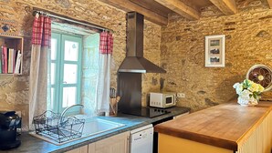 A rustic kitchen with a stone wall, wooden beams, a built-in stove, a microwave, and a sink. - Gîte for 2 people with swimming pool - In the heart of Périgord noir (Saint-Cyprien)