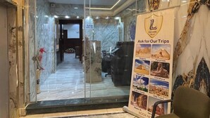 A hotel lobby with a marble floor, a reception desk, and a signboard advertising tours to various destinations. - lora Altahrir hotel (Cairo)