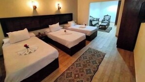 A hotel room with three beds, a patterned rug, and a view of the outside. - lora Altahrir hotel (Cairo)