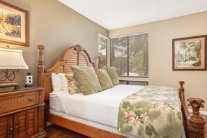 Une chambre à coucher avec un lit en bois, une table de chevet, une lampe et une fenêtre avec des stores.