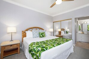 Een hotelkamer met een bed, nachtkastjes, een spiegel en een badkamer met een wastafel en spiegel.
