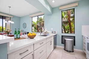A modern kitchen with a large island, a sink, and a trash can. - Grand Champions | Ocean View 4 BR, Sleeps 14 | Car Incl. w/ 6+ Nights | GCH ML-1496 by KBM (Wailea)