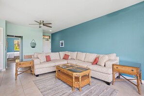 A living room with a sectional sofa, a glass-top coffee table, and two side tables. - Grand Champions | Ocean View 4 BR, Sleeps 14 | Car Incl. w/ 6+ Nights | GCH ML-1496 by KBM (Wailea)