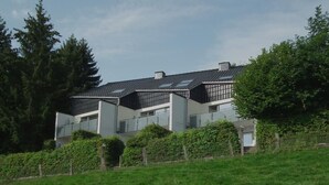 Une maison moderne à deux étages, dotée d’un toit en pente, de grandes fenêtres et d’une pelouse devant.