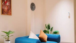Ein Zimmer mit einem blauen Sofa, einer Wanduhr und einem Gemälde über dem Sofa.