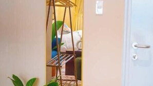 Ein Zimmer mit Holzboden, einem Blumentopf, einem Spiegel an der Wand und einer Tür.