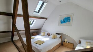 A bedroom with a sloped ceiling, a bed with white linens, a wooden headboard, a nightstand, a lamp, and a painting on the wall. - St Martins Walk - Three Bedroom Apartment, Sleeps 6 (York)