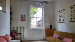 A living room with a sofa, a chair, a radiator, a window, and wall art. - St Martins Walk - Three Bedroom Apartment, Sleeps 6 (York)
