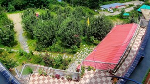 A rooftop terrace with a red roof, a checkered floor, and a view of a mountainous landscape.