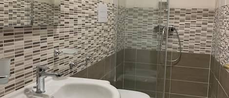 A modern bathroom with a glass-enclosed shower, a sink, and a toilet.