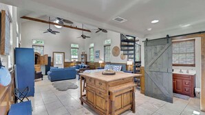 A spacious living area with a central wooden coffee table, a blue sofa, and a staircase leading to an upper level.