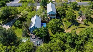 An aerial view of a residential property with two main buildings, a swimming pool, and a playground.