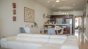 A modern living room with a white sofa, a dining area with a table and chairs, and a kitchen in the background. - Beachfront apartment in Akumal U3 (Akumal)