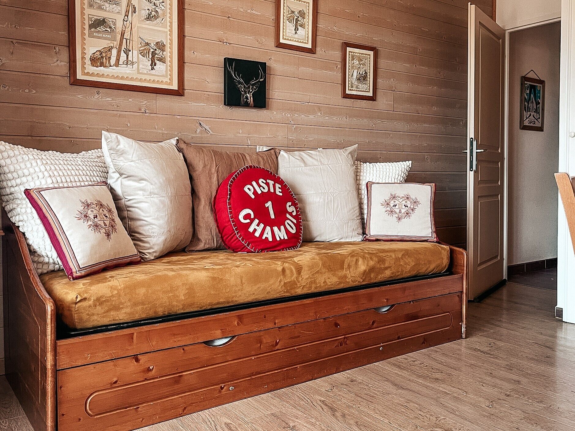 A wooden wall with framed pictures, a sofa with decorative pillows, and a door.