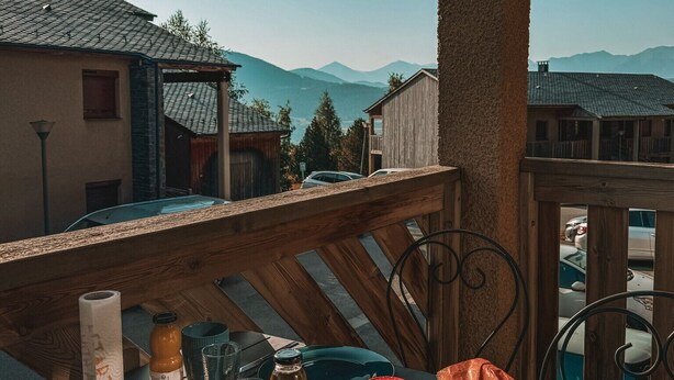 Ein Tisch im Freien mit Blick auf Berge, einem Holgitter und einem klaren Himmel.