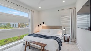 A bedroom with a large window, a bed, a bedside table, a bench, and a ceiling fan. - The Modern Cottage near 30a, Golf Cart + Bikes included! (Inlet Beach)