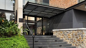 A modern building with a stone facade, a black metal staircase, and a glass entrance. - The Signature | Lush Designer Apartment (Cape Town)