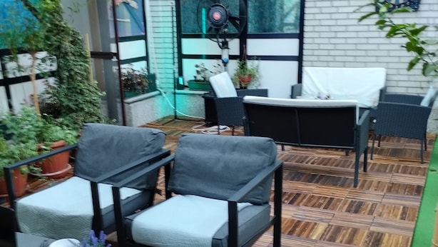 An outdoor patio area with wooden flooring, black metal chairs, a table with a white tablecloth, and potted plants. - Hostel Put Svile-Hostel Silk Road (Subotica)