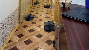 A hotel hallway with a checkered floor, wooden doors, and a potted plant on a desk. - Hostel Put Svile-Hostel Silk Road (Subotica)