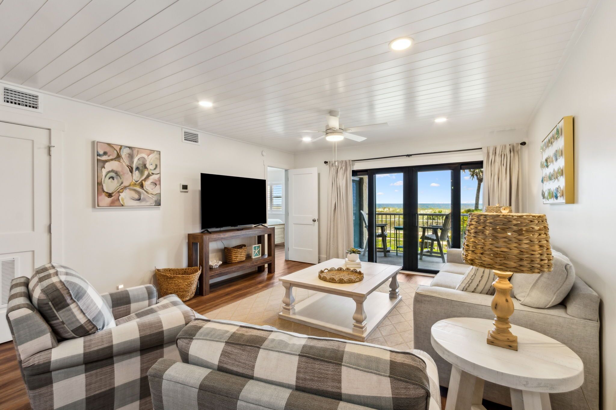 A living room with a sofa, a coffee table, a TV, and a view of the outdoors.