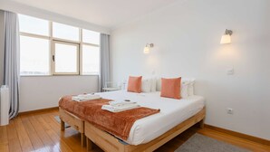 A modern hotel room with a large bed, two wall-mounted lights, a window with curtains, and a view of the city. - Liiiving in Gaia - Douro Balcony View (Vila Nova de Gaia)