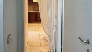 Pasillo que conduce a una cocina con piso de baldosas y gabinetes de madera.