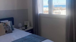 A bedroom with a bed, a nightstand, a lamp, and a view of the sea. - House on the Beach, House on the beach near the airport (Isola Sacra)
