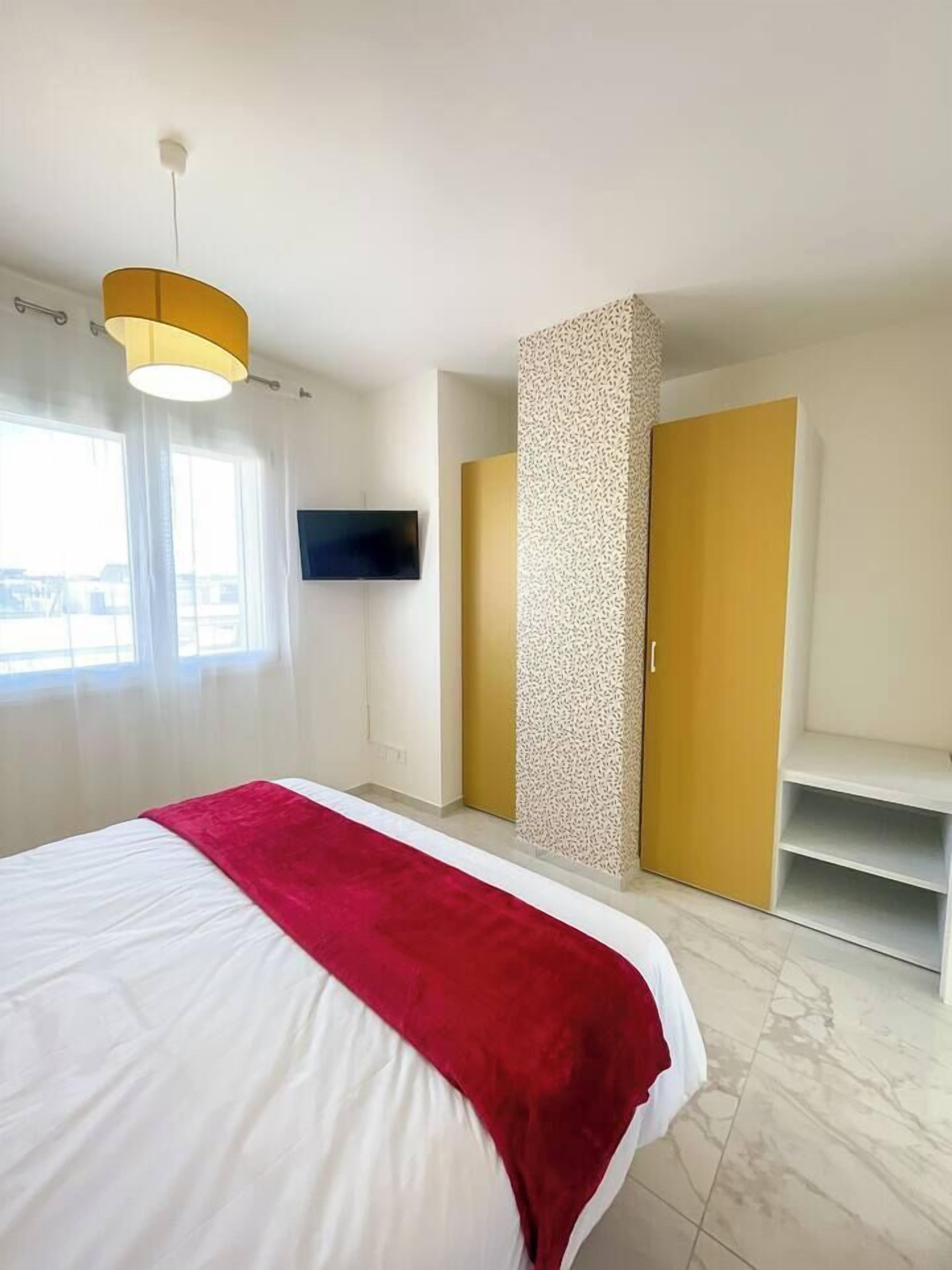 Une chambre d’hôtel comprenant un lit, un téléviseur fixé au mur, une armoire et un petit coin salon.