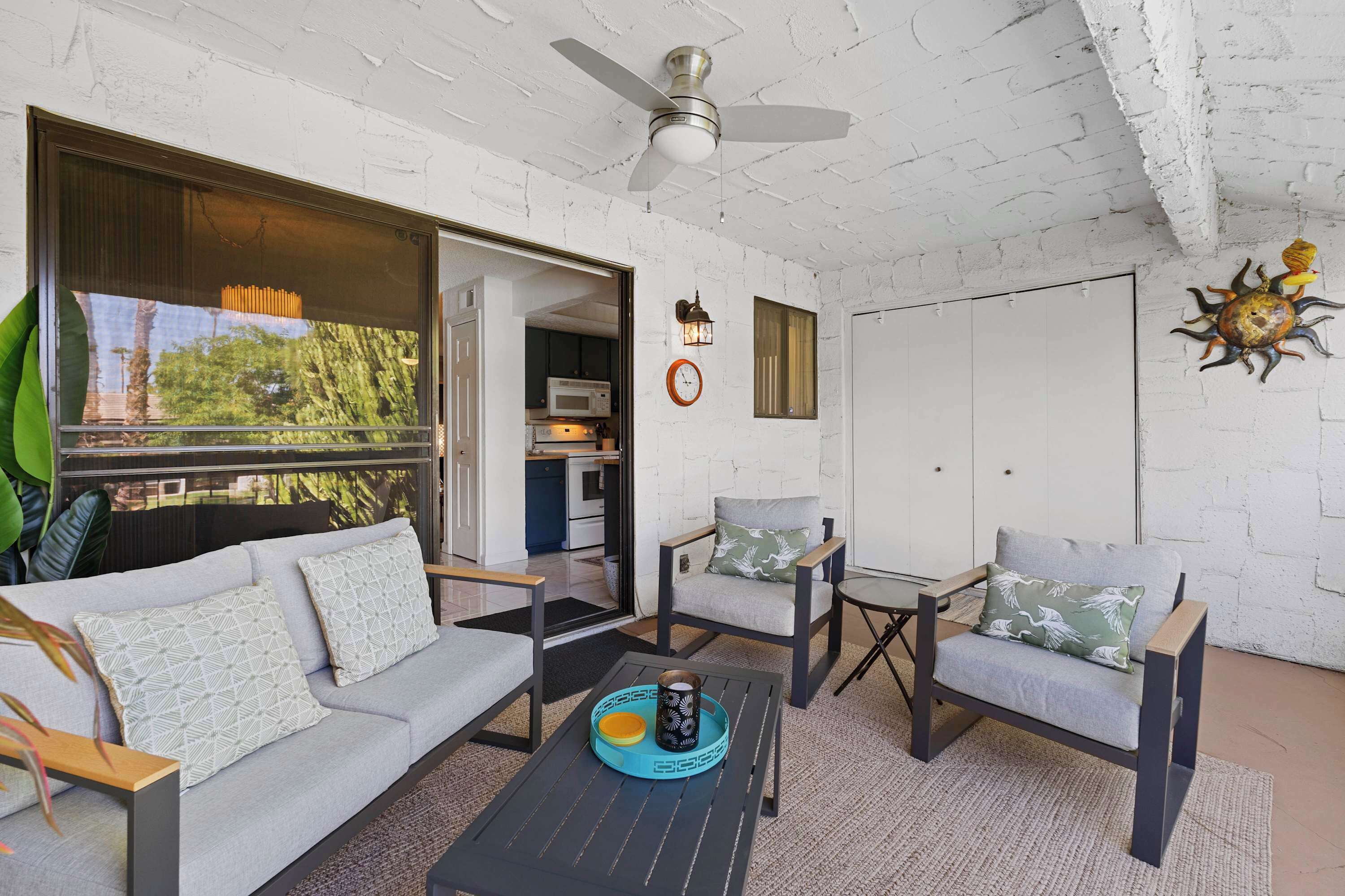 A modern living room with a sofa, chairs, a coffee table, and a ceiling fan.