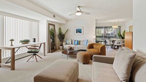 Ein geräumiges Wohnzimmer mit einer Couch, Sesseln, einem Couchtisch und einem Essbereich im Hintergrund.