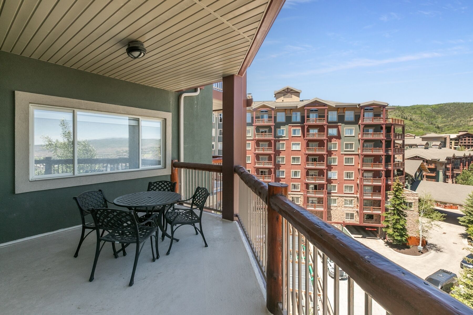 A balcony with a table and chairs, overlooking a multi-story building with balconies.