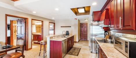 A spacious kitchen with a central island, wooden cabinets, and a dining area with a table and chairs.
