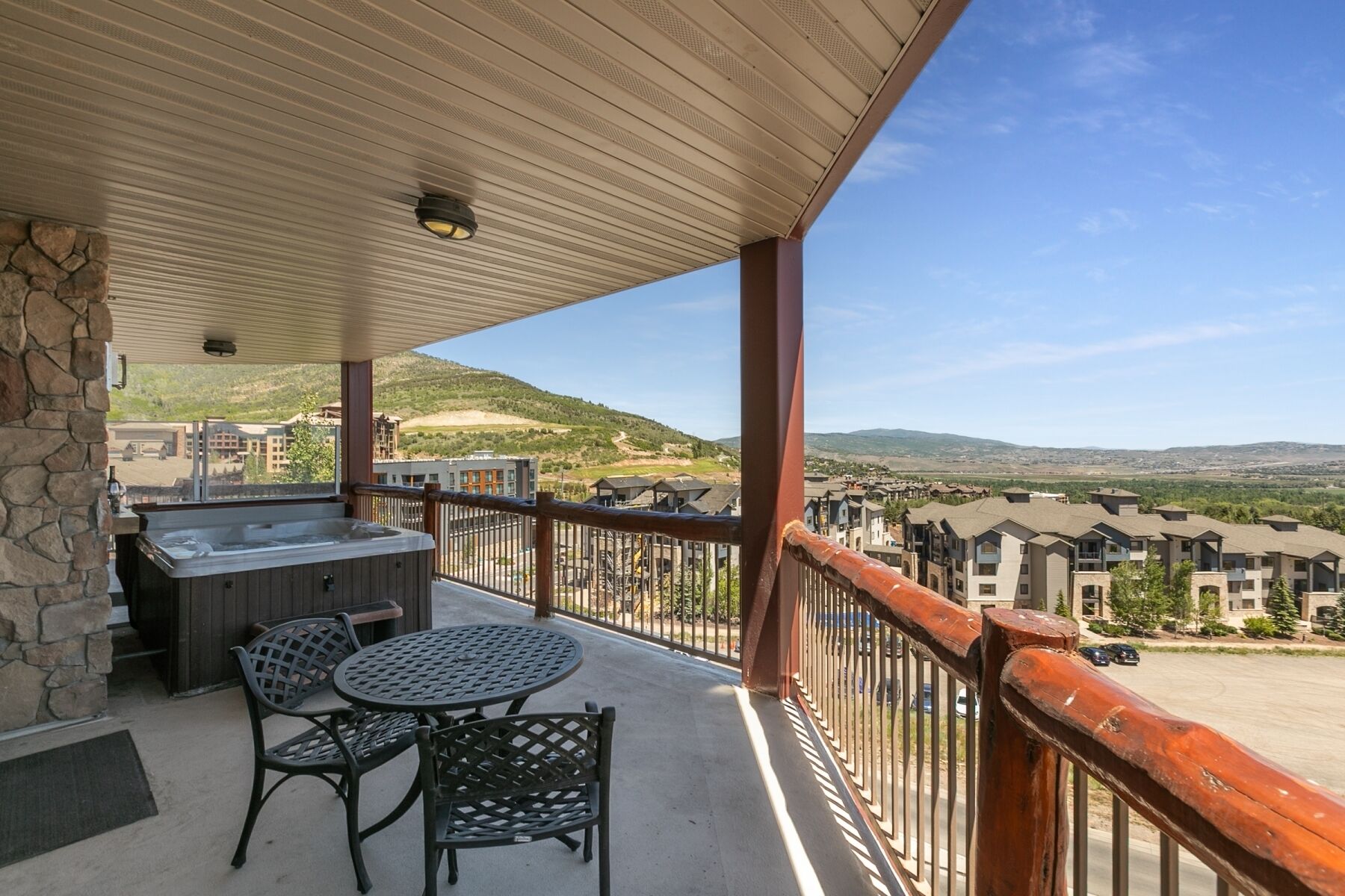 A balcony with a hot tub, outdoor seating, and a view of a residential area.