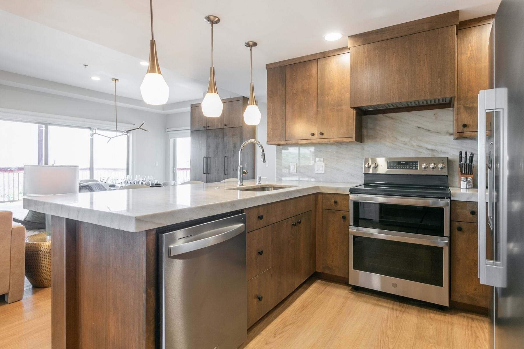 A modern kitchen with wooden cabinets, stainless steel appliances, and pendant lighting.