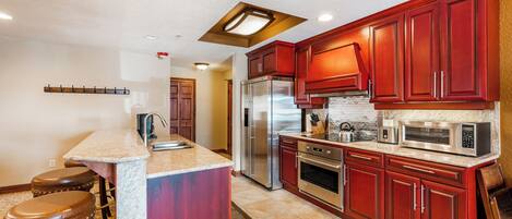 Una cocina con una isla central, electrodomésticos de acero inoxidable y armarios rojos.