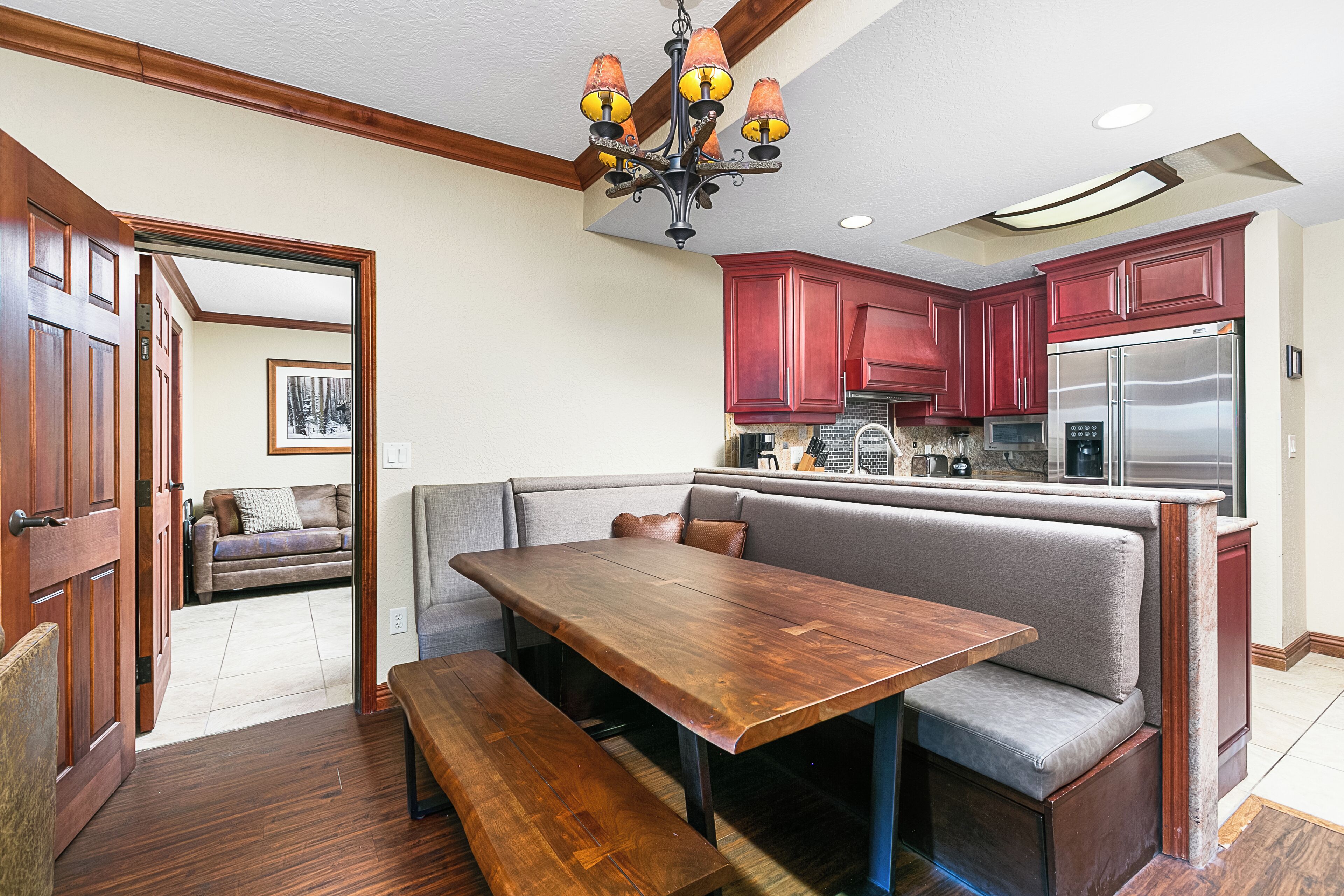 Una cocina con un banco integrado, una mesa de comedor de madera y un refrigerador de acero inoxidable.