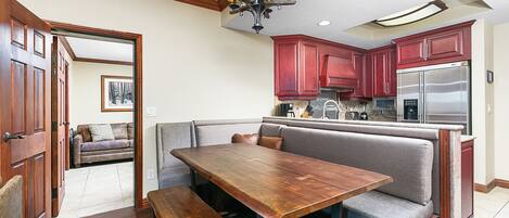 Una cocina con un banco integrado, una mesa de comedor de madera y un refrigerador de acero inoxidable.