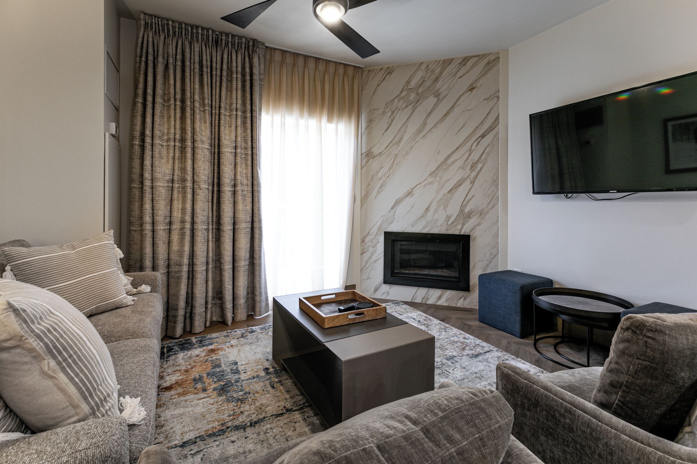 A modern living room with a sofa, a coffee table, a fireplace, and a television mounted on the wall.