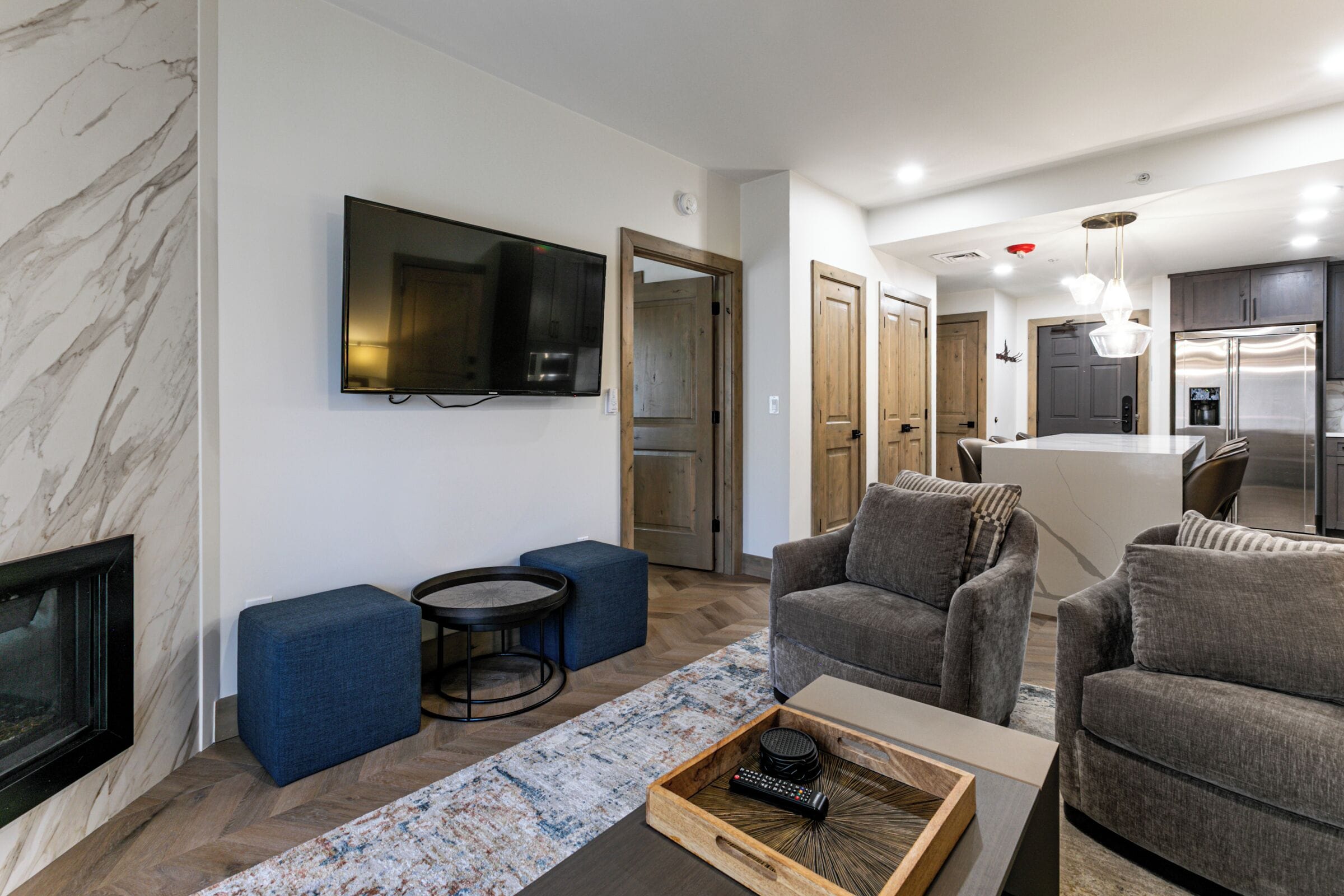 A modern living room with a flat-screen TV, grey sofas, a coffee table, and a fireplace.