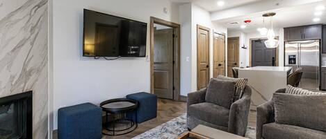 Una sala de estar moderna con un televisor de pantalla plana, sofás grises, una mesa de centro y una chimenea.