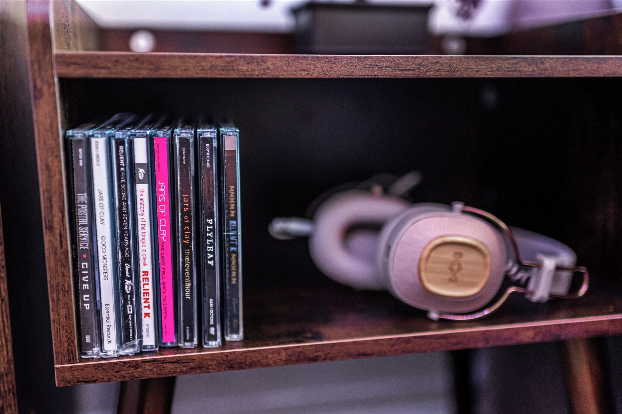 Uno scaffale di legno con una fila di CD e una tazza rosa.