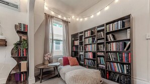Une chambre confortable avec une grande bibliothèque, un lit douillet et une petite table agrémentée d’une plante.