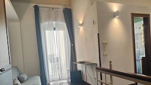 A modern living room with a sofa, a small table, and a staircase leading to an upper level. - Dimora San Triggiano (Bari)